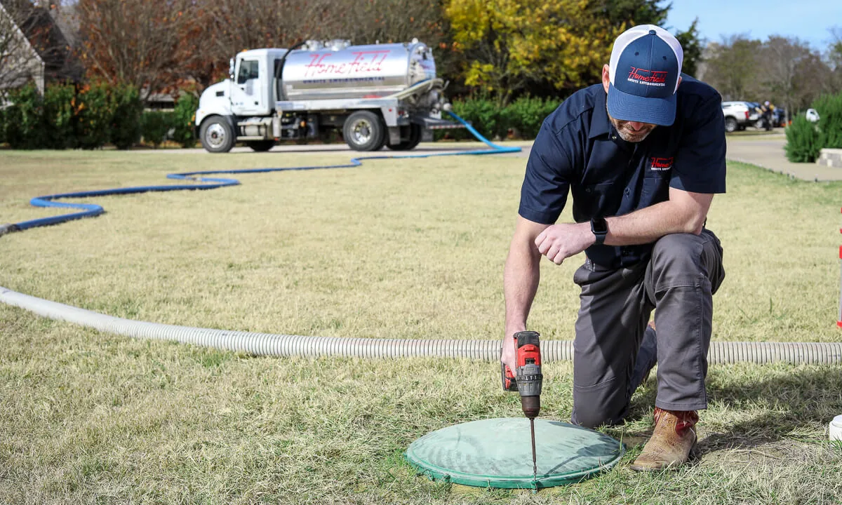 HomeField technician opening a septic riser lid on a lawn