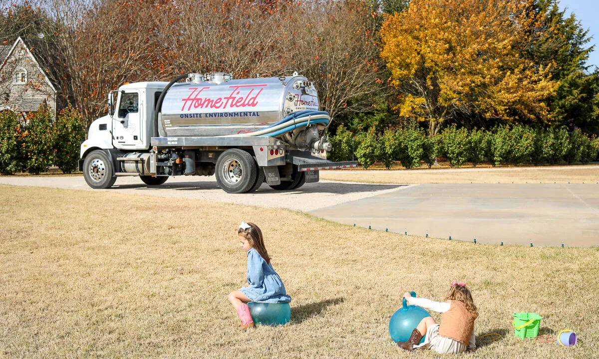 HomeField pump truck in a home's driveway while two girls play on the lawn