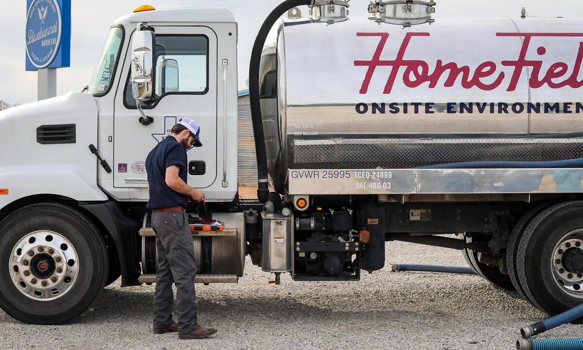 HomeField technician reviewing a checklist beside a service truck in a gravel parking lot