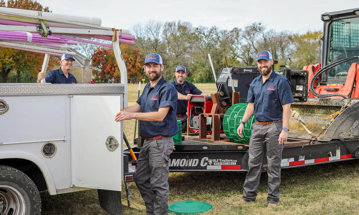 HomeField crew smiling beside a service truck and a loaded trailer
