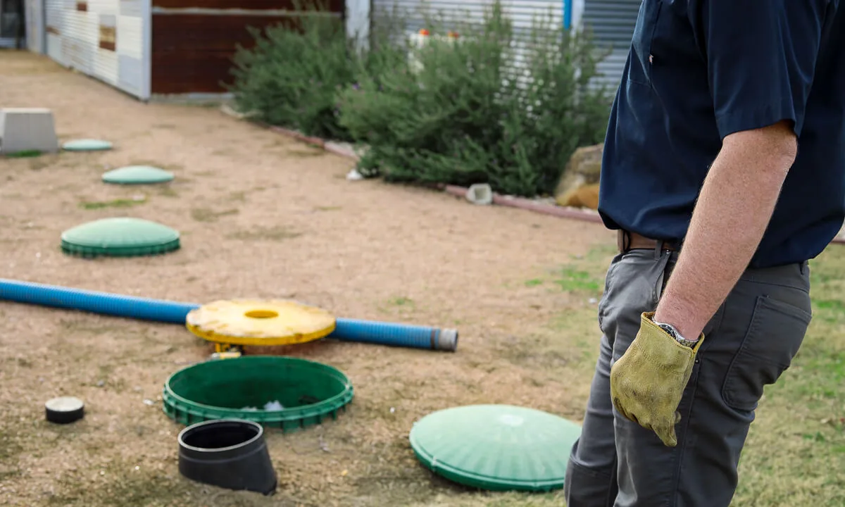 HomeField technician beside a row of green septic risers outside a commercial building