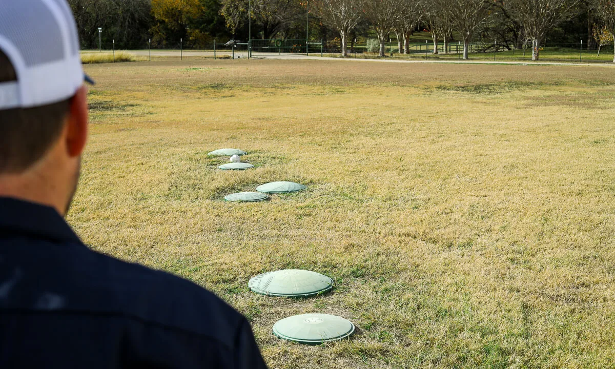 Crew member looking across a lawn at a row of septic risers