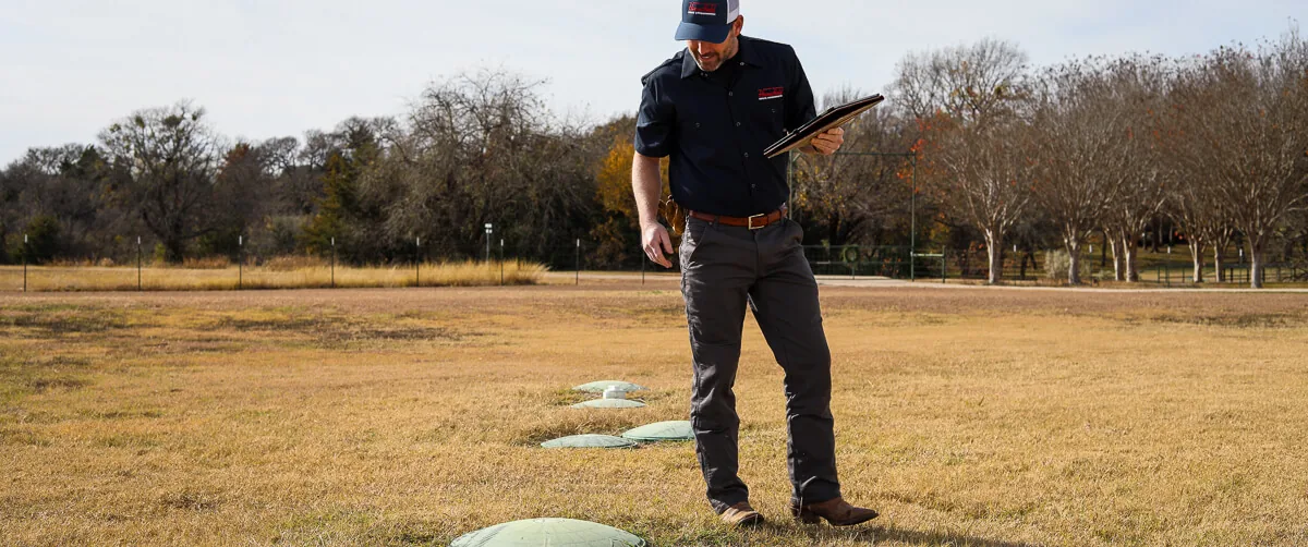 HomeField technician checking septic tank risers in a lawn