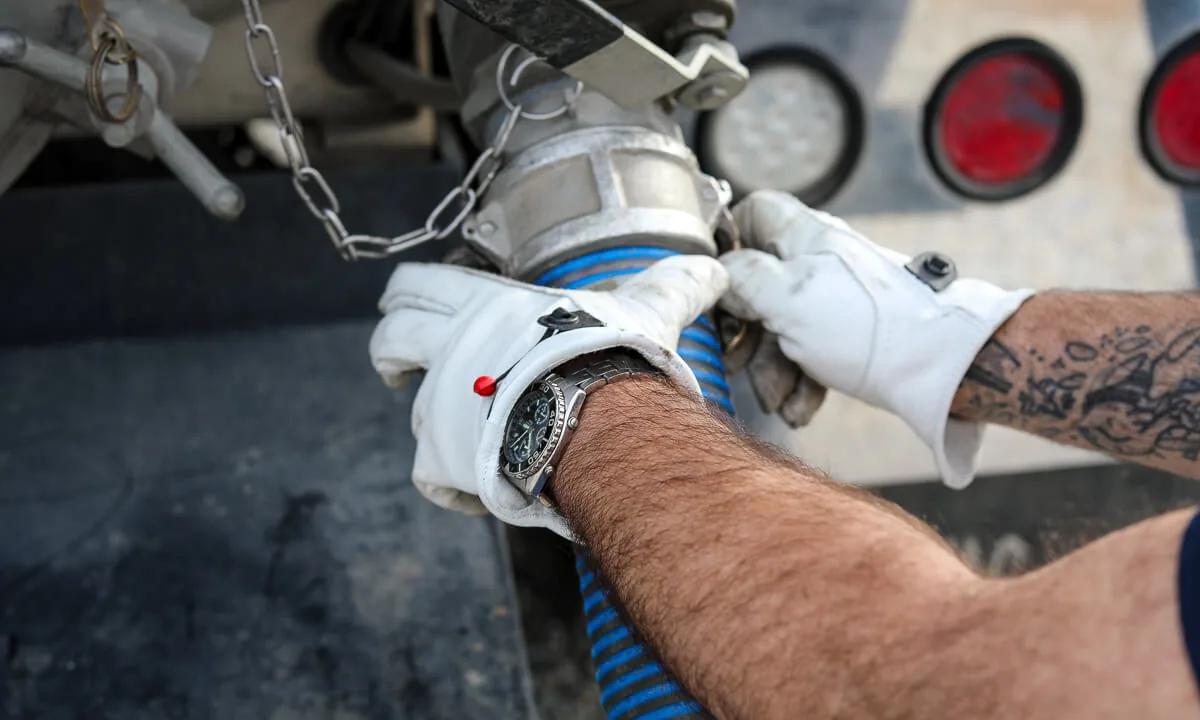 Gloved hands connecting a camlock fitting on a septic suction hose