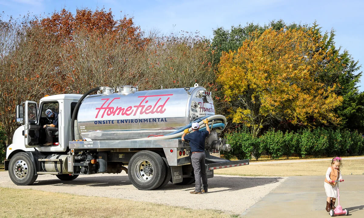 HomeField crew finishing a pump-out while a child plays in the driveway