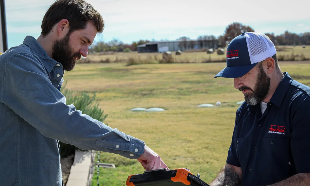 Homeowner pointing at a septic layout on a HomeField technician's tablet