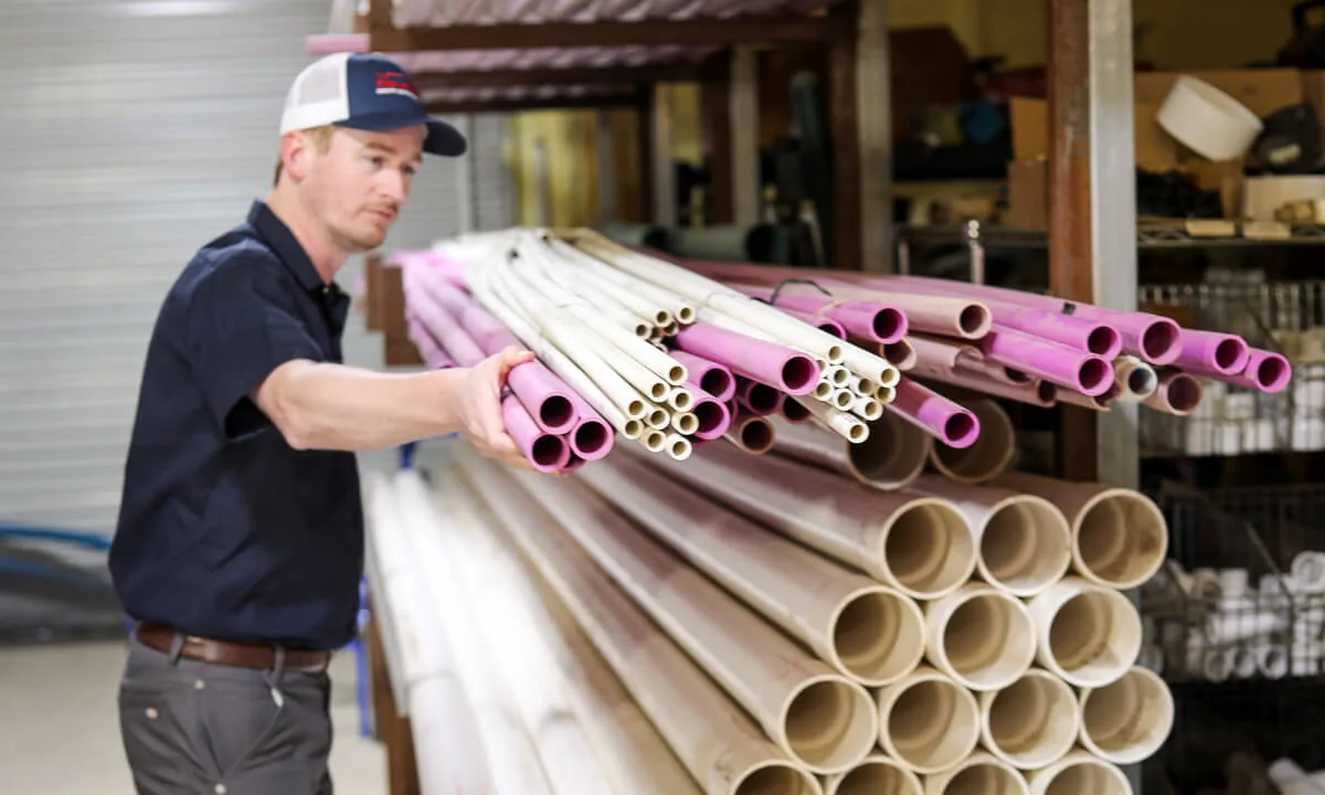 HomeField technician looking over a stack of PVC pipe in a supply warehouse