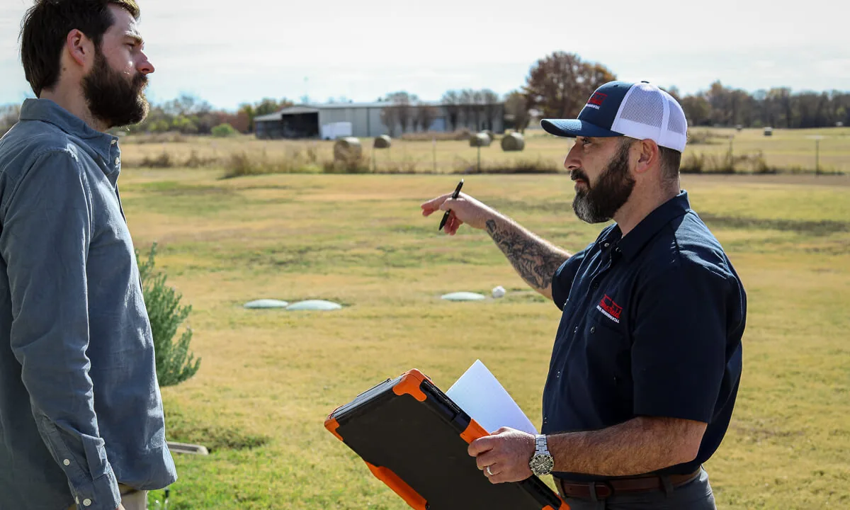 HomeField technician pointing out septic riser lids in a yard to a homeowner