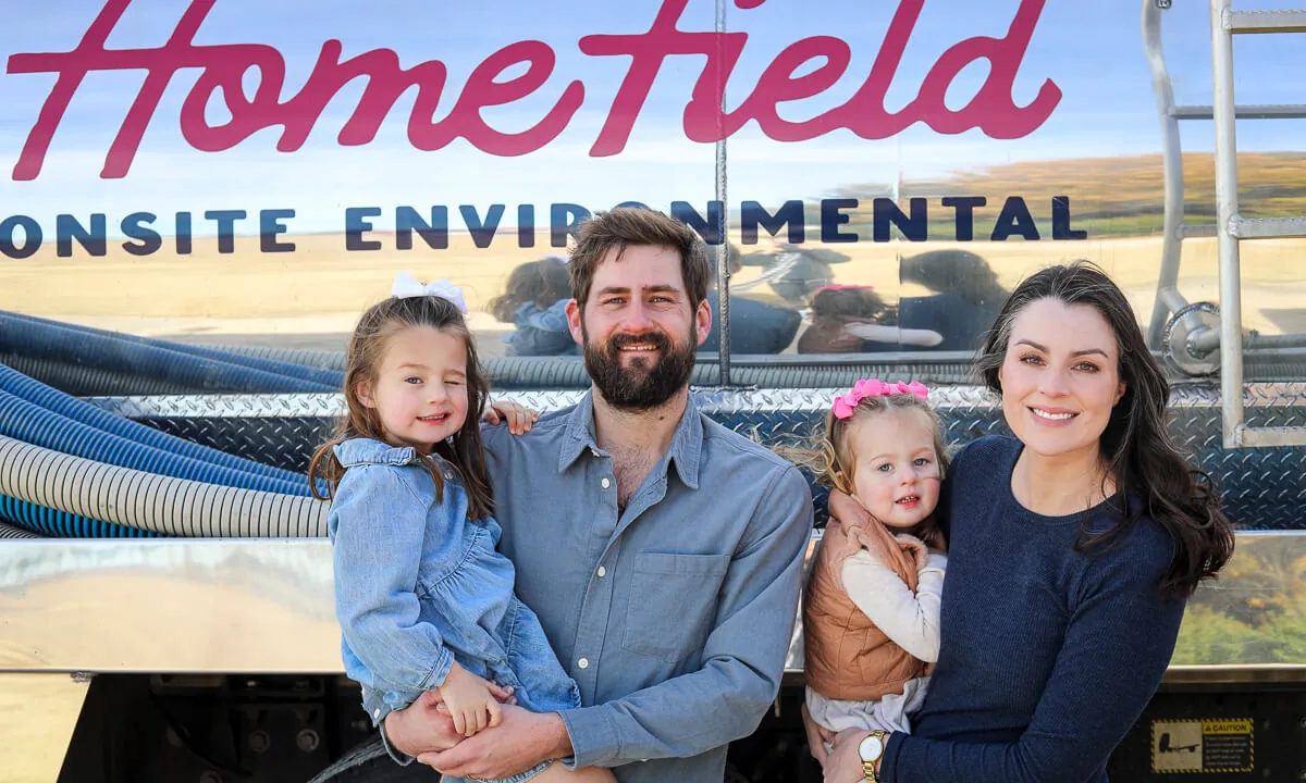 Family standing in front of a HomeField septic pump truck