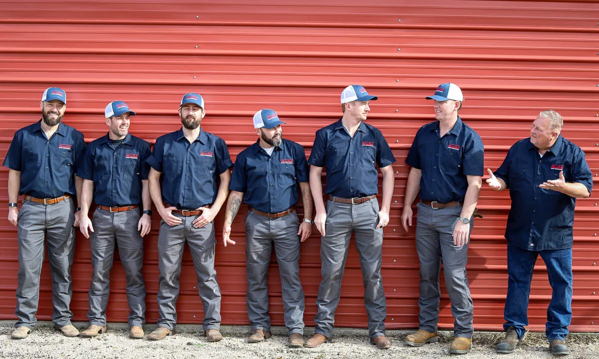 HomeField crew members laughing together in front of a red metal wall